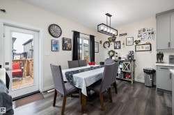 Dining area featuring wood-finish flooring, a contemporary linear chandelier, and a white framed patio door - 