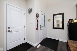 Foyer entrance featuring a white paneled door, wood-finish flooring, and a second door with an integrated glass panel - 