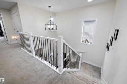 Carpeted staircase featuring a white railing with dark metal balusters - 