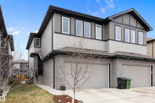 Contemporary two-story exterior featuring a two-car garage, stone veneer accents, and multi-pane windows - 84 Wingate Way, Fort Saskatchewan, AB 