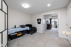 Spacious carpeted room featuring a ceiling-mounted light fixture, white walls, and a wide entryway to an additional room - 