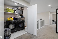 Dedicated laundry area featuring a front-loading washer and dryer, recessed lighting, and white shelving for storage - 