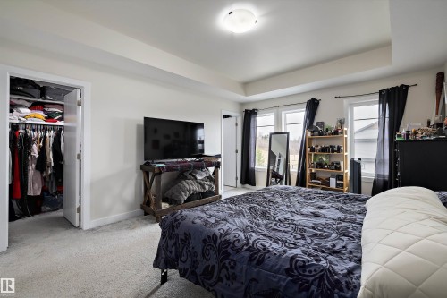 Bright room featuring three windows with dark drapes, light-toned walls, and a tray ceiling - 84 Wingate Way, Fort Saskatchewan, AB 