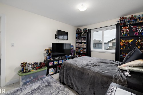 Bedroom featuring a double-pane window, carpet flooring, a flush-mount ceiling light fixture, and light-toned wall paint - 84 Wingate Way, Fort Saskatchewan, AB 