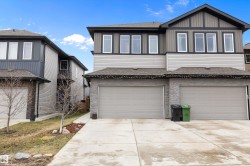 Modern duplex exterior featuring a two-car garage, stone veneer siding, light gray horizontal siding, dark vertical siding, and a concrete driveway - 