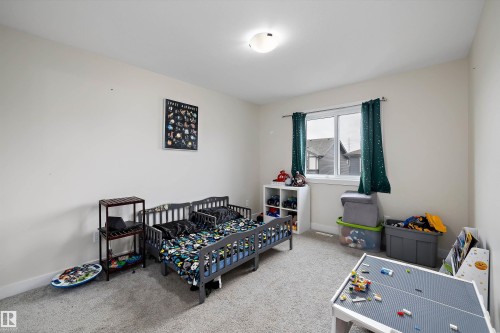 Light-filled room featuring neutral wall tones, textured carpet flooring, and a flush-mount ceiling light fixture - 84 Wingate Way, Fort Saskatchewan, AB 