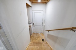 Unfinished basement stairs featuring plywood treads and risers, a wood handrail with metal brackets, and drywall walls - 