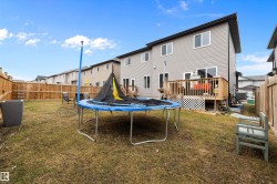 Spacious backyard featuring a wooden privacy fence, a multi-level deck with wooden railings, and gray vinyl siding on the property - 