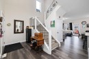 Foyer featuring an open-concept design with high ceilings, recessed lighting, wood-finish flooring, and a carpeted staircase with white risers and black metal spindles - 84 Wingate Way, Fort Saskatchewan, AB 
