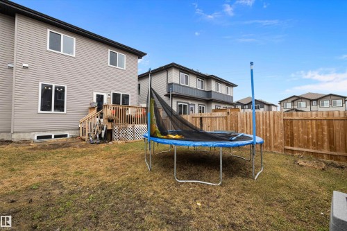 Rear exterior featuring light gray siding and a wooden deck with railing - 84 Wingate Way, Fort Saskatchewan, AB 