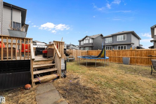 Rear yard featuring a wood deck with stairs, a full privacy fence, and a grass area - 84 Wingate Way, Fort Saskatchewan, AB 