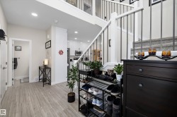 Entryway featuring wood-finish flooring, white trim, recessed lighting, and a staircase with white risers and dark metal balusters - 