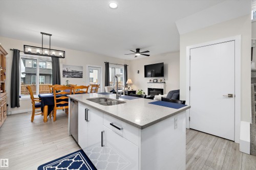 Bright open-concept living space featuring a kitchen island with an undermount sink, light-toned countertops, and integrated stainless steel appliances - 84 Wingate Way, Fort Saskatchewan, AB 