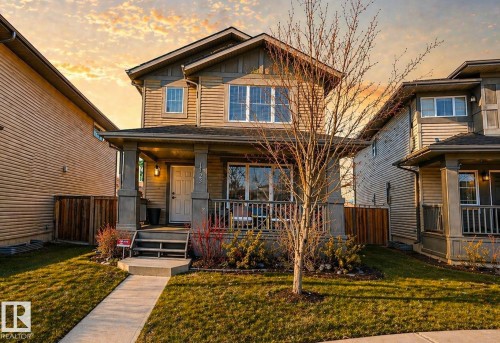 Two-story home with a covered front porch featuring stone-clad pillars and a wood-paneled exterior - 1148 35 Avenue, Edmonton, AB - Outdoor With Deck Patio Veranda