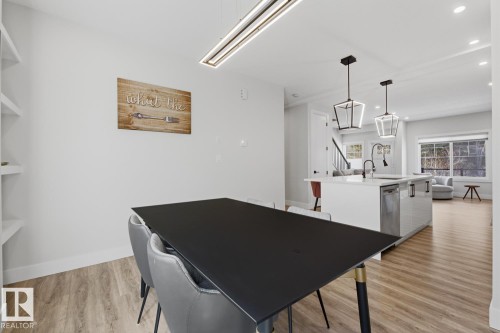 Open-concept dining area with wood-finish flooring, featuring a linear ceiling light fixture and built-in shelving - 61 230 Edgemont Road, Edmonton, AB - Indoor Photo Showing Other Room