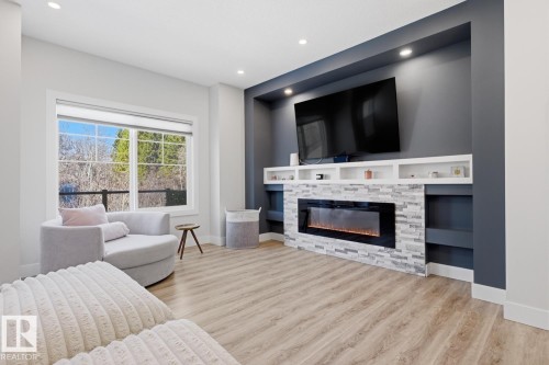 Living area featuring light wood-finish flooring and a large window - 61 230 Edgemont Road, Edmonton, AB - Indoor Photo Showing Living Room With Fireplace