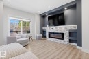Living area featuring light wood-finish flooring and a large window - 61 230 Edgemont Road, Edmonton, AB  - Indoor Photo Showing Living Room With Fireplace 