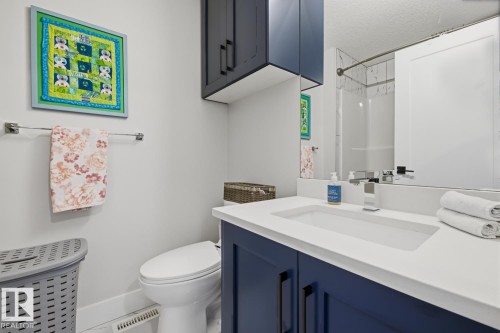 Bathroom featuring a vanity with a white countertop and integrated sink, blue-finish cabinetry, and a full-width wall mirror - 61 230 Edgemont Road, Edmonton, AB - Indoor Photo Showing Bathroom