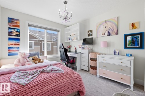 Bright bedroom with a large window, a built-in desk with shelving, and light-colored carpet - 61 230 Edgemont Road, Edmonton, AB - Indoor Photo Showing Bedroom