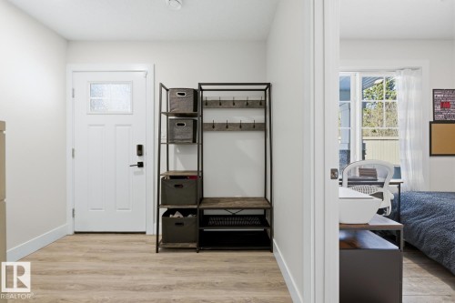 Entryway featuring wood-finish flooring, white trim, and a white paneled door with a frosted glass insert - 61 230 Edgemont Road, Edmonton, AB - Indoor Photo Showing Other Room