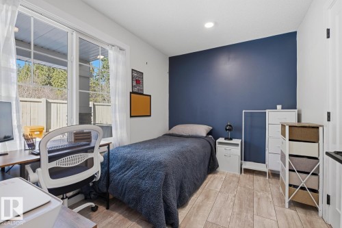 Room featuring wood-finish flooring, a prominent accent wall, recessed lighting, and sliding glass doors with direct outdoor access - 61 230 Edgemont Road, Edmonton, AB - Indoor Photo Showing Bedroom