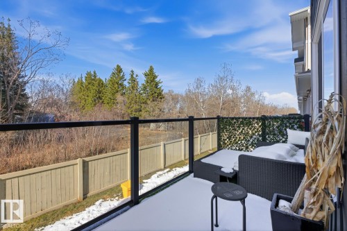 Exterior deck featuring a glass and black metal railing, privacy screening, and a wooden fence bordering the property - 61 230 Edgemont Road, Edmonton, AB - Outdoor With Balcony With Exterior