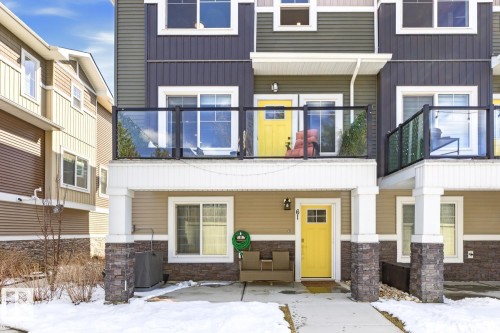 Contemporary townhome exterior featuring multi-toned siding, decorative stone accents, and bright yellow entry doors - 61 230 Edgemont Road, Edmonton, AB - Outdoor With Balcony With Facade