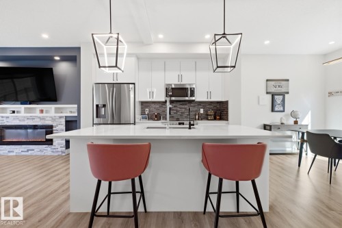 Open-concept kitchen featuring an oversized island with white countertop, recessed lighting, and stainless steel appliances - 61 230 Edgemont Road, Edmonton, AB - Indoor Photo Showing Kitchen With Stainless Steel Kitchen With Upgraded Kitchen