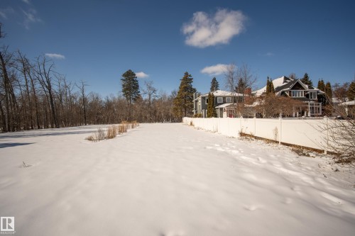 Expansive snow-covered grounds bordered by a white fence and mature trees - 9209 96 Street Nw, Edmonton, AB 