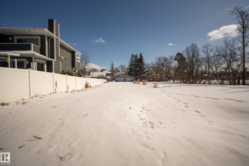 The property features an extensive snow-covered yard, bordered by a white fence - 9209 96 Street Nw, Edmonton, AB 