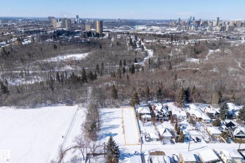 Aerial view of the property, outlined in orange, situated in a snow-covered landscape with surrounding bare trees and evergreen trees - 9209 96 Street Nw, Edmonton, AB 