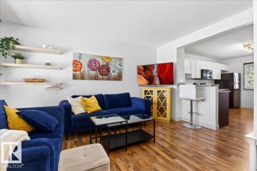 Open-concept living space with wood-finish flooring, white walls, and recessed lighting - 18 6032 38 Avenue, Edmonton, AB - Indoor
