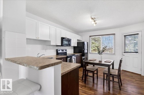 Kitchen featuring white upper cabinetry, dark base cabinetry, laminate countertops, and stainless steel appliances - 18 6032 38 Avenue, Edmonton, AB - Indoor