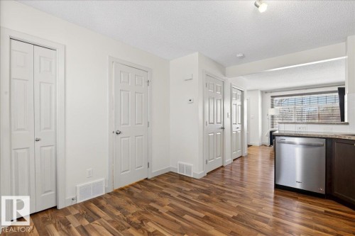 Open-concept living space with wood-finish flooring, white trim, and a built-in stainless steel dishwasher - 18 6032 38 Avenue, Edmonton, AB - Indoor Photo Showing Other Room
