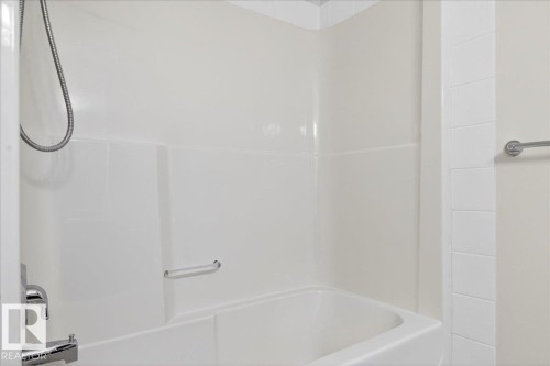 White bathtub with integrated shower, chrome fixtures, and a wall-mounted towel bar - 18 6032 38 Avenue, Edmonton, AB - Indoor Photo Showing Bathroom