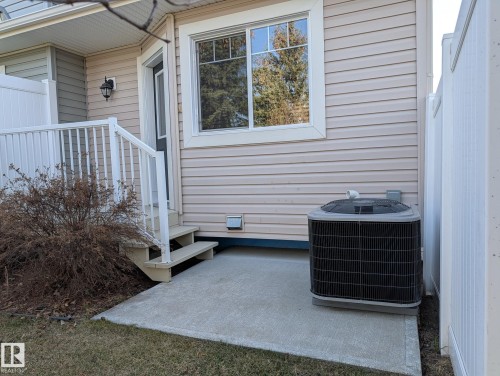 Rear exterior featuring beige horizontal siding, white trim, a concrete patio, and a central air conditioning unit - 18 6032 38 Avenue, Edmonton, AB - Outdoor With Exterior