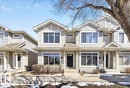 Townhome exterior with light-colored siding, contrasting trim, and multiple large windows - 18 6032 38 Avenue, Edmonton, AB  - Outdoor With Facade 