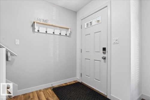 Entryway featuring wood-finish flooring, a white paneled door with glass inserts, and a digital keyless entry system - 18 6032 38 Avenue, Edmonton, AB - Indoor Photo Showing Other Room