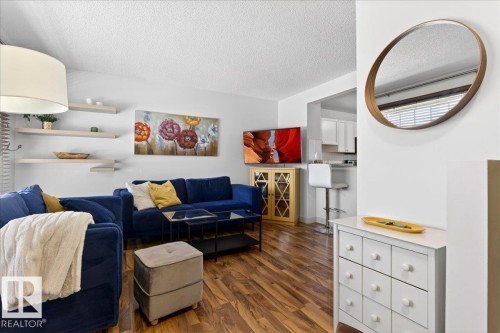 Open-concept living space featuring wood-finish flooring, white walls, and a recessed kitchen pass-through - 18 6032 38 Avenue, Edmonton, AB - Indoor Photo Showing Living Room