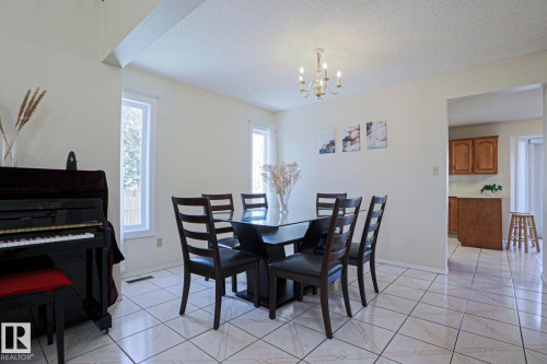 Dining area featuring ceramic tile flooring, a chandelier, and multiple windows - 2433 89 Street, Edmonton, AB - Indoor Photo Showing Dining Room