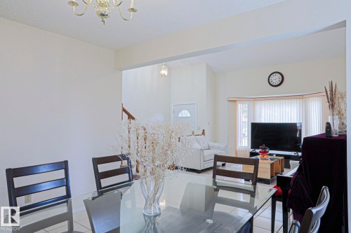 Open-concept living area featuring a bay window with vertical blinds, tile flooring, and a chandelier lighting fixture - 2433 89 Street, Edmonton, AB - Indoor