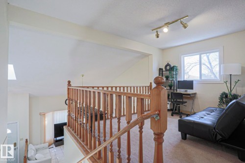 Upper level featuring wood baluster railing, carpet flooring, a white-framed window, and track lighting - 2433 89 Street, Edmonton, AB - Indoor
