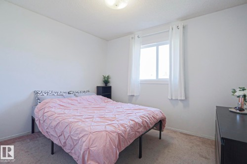 Room featuring a large window with white trim, light-colored walls, and neutral carpeting - 2433 89 Street, Edmonton, AB - Indoor Photo Showing Bedroom