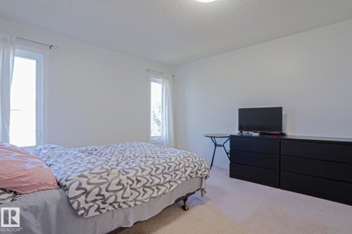 Bright room with two vertical windows featuring light-colored window treatments - 2433 89 Street, Edmonton, AB - Indoor Photo Showing Bedroom