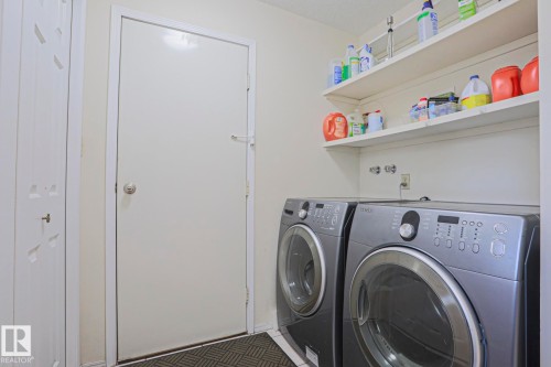 Dedicated laundry area featuring a washer and dryer, integrated wall shelving, and neutral wall finishes - 2433 89 Street, Edmonton, AB - Indoor Photo Showing Laundry Room