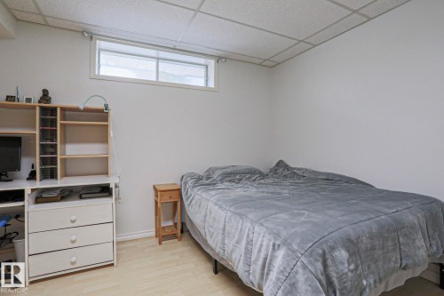 Light-toned wood-finish flooring complements white walls and a drop ceiling - 2433 89 Street, Edmonton, AB - Indoor Photo Showing Bedroom
