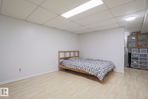 Spacious room featuring light wood-finish flooring, white baseboards, and a dropped ceiling with integrated lighting - 2433 89 Street, Edmonton, AB - Indoor Photo Showing Bedroom
