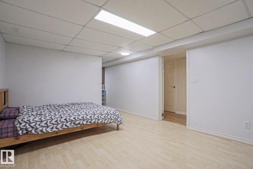 Spacious room featuring light wood-finish flooring, white walls, and a dropped ceiling with recessed lighting - 2433 89 Street, Edmonton, AB - Indoor Photo Showing Bedroom