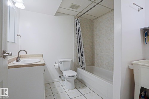 Full bathroom featuring a white vanity with integrated sink, a toilet, and a bathtub with tile surround - 2433 89 Street, Edmonton, AB - Indoor Photo Showing Bathroom