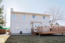 Rear exterior featuring light-colored siding, a multi-level wood deck, and a grass lawn - 2433 89 Street, Edmonton, AB  - Outdoor With Deck Patio Veranda With Exterior 